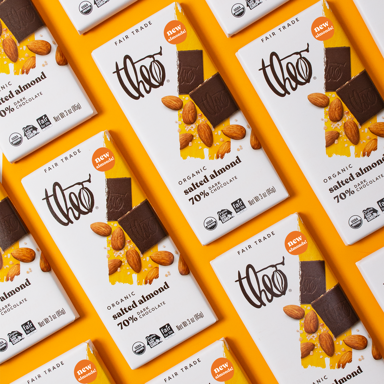 Multiple bars of Theo Organic Salted Almond 70% Dark Chocolate on a yellow background