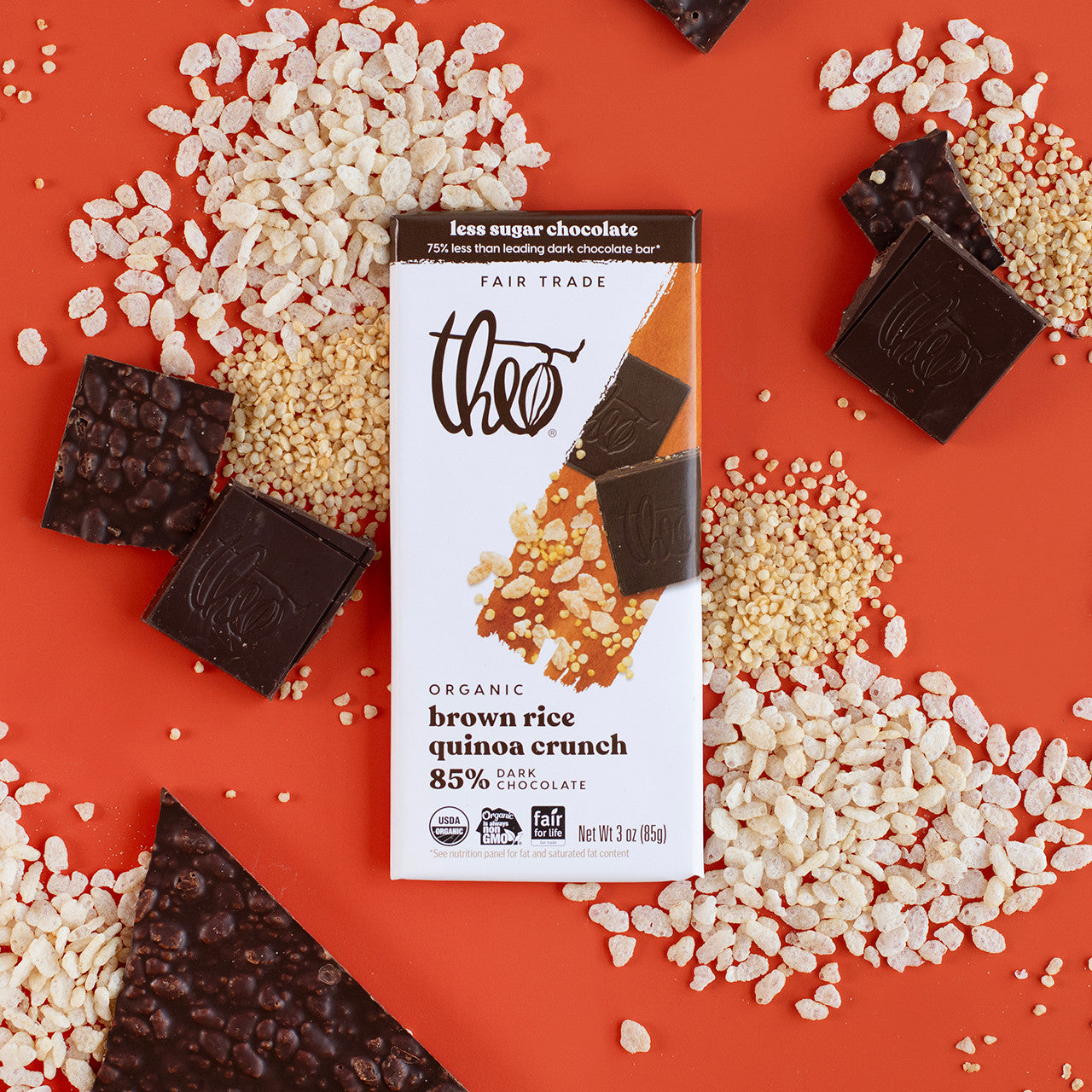 Bar of 85% dark chocolate with brown rice quinoa crunch on a red background with rice crisps and quinoa.