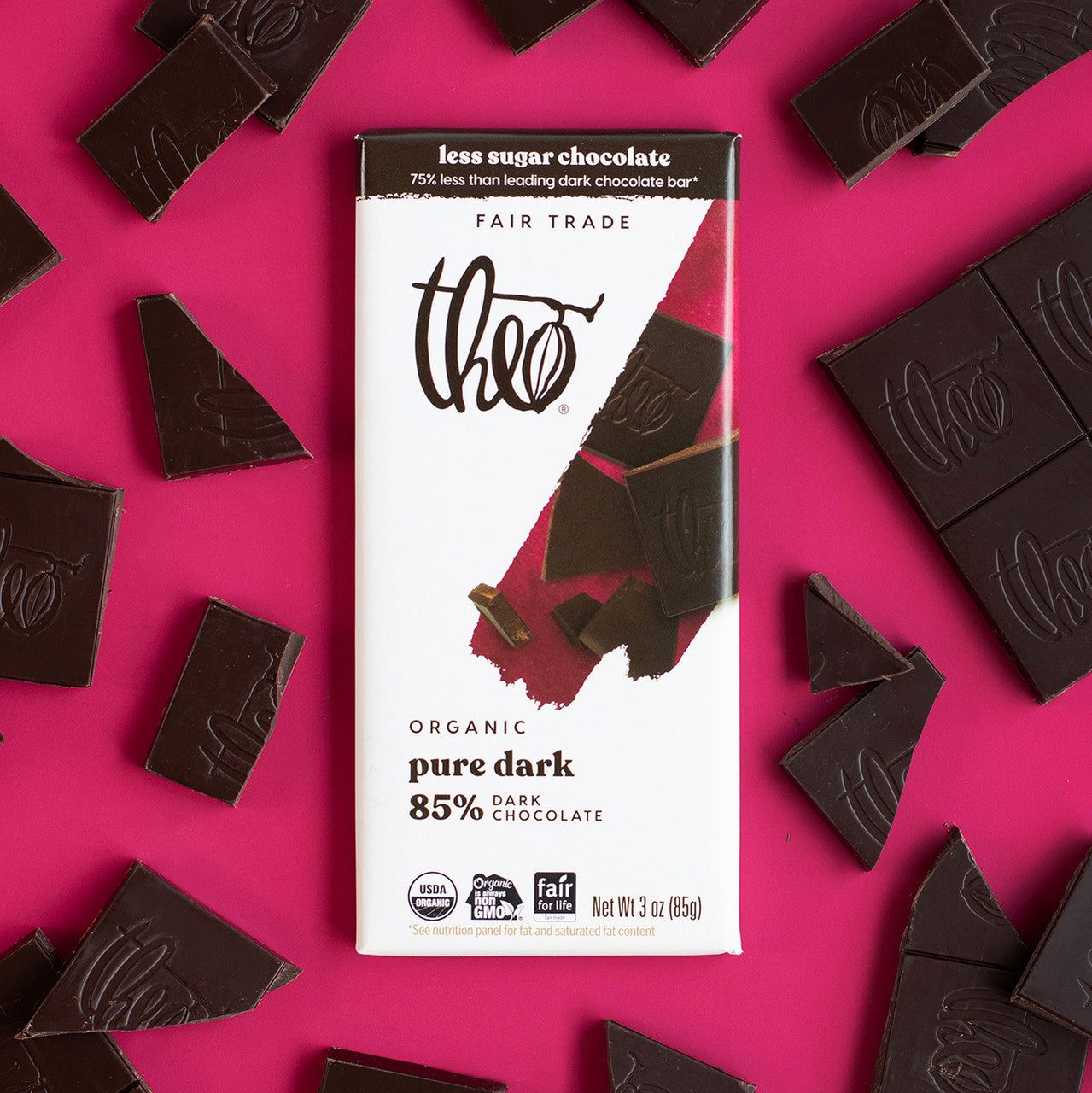 Theo organic pure dark 85% chocolate bar packaging on a pink background with chocolate pieces around.