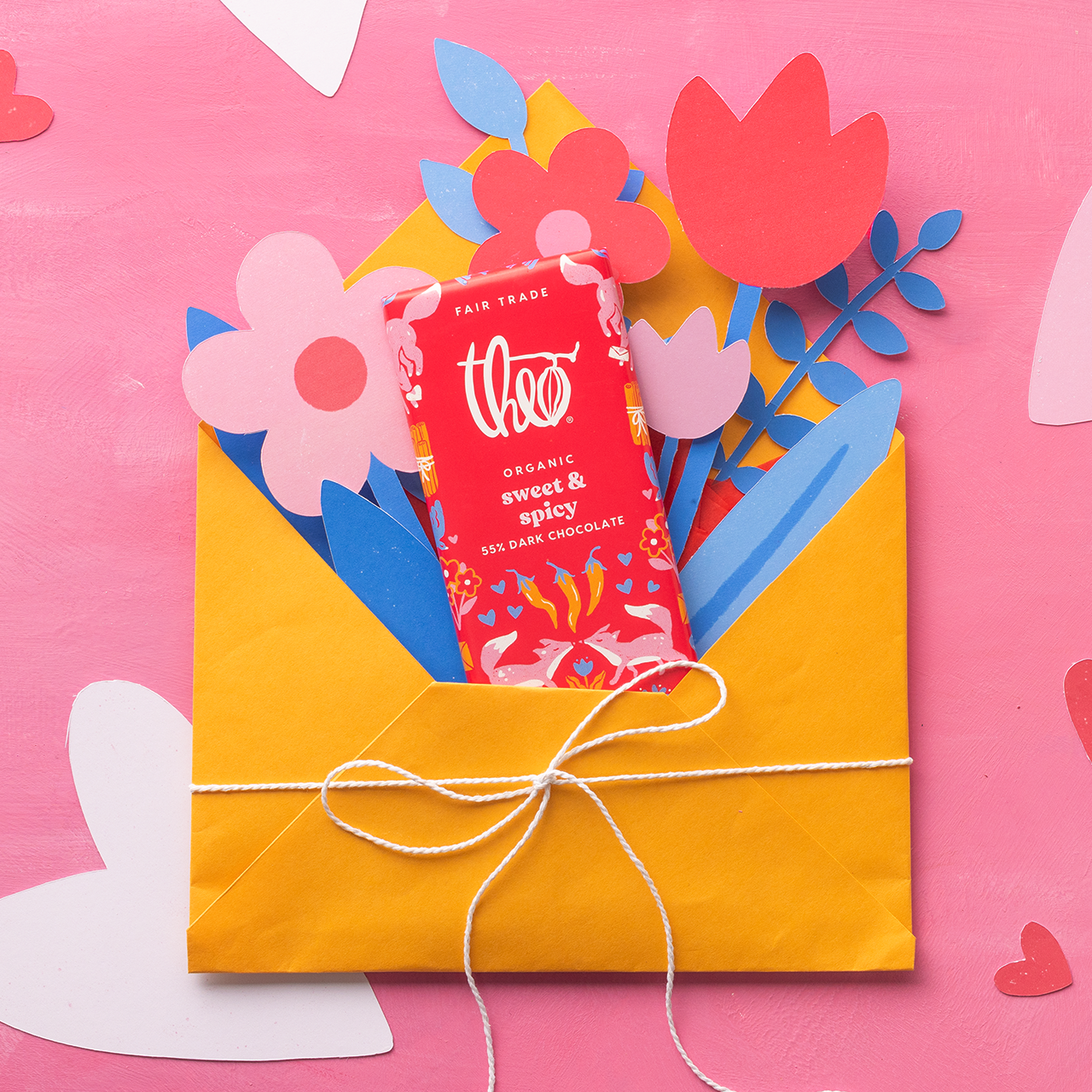 Yellow envelope with a red chocolate bar and colorful flowers on a pink background