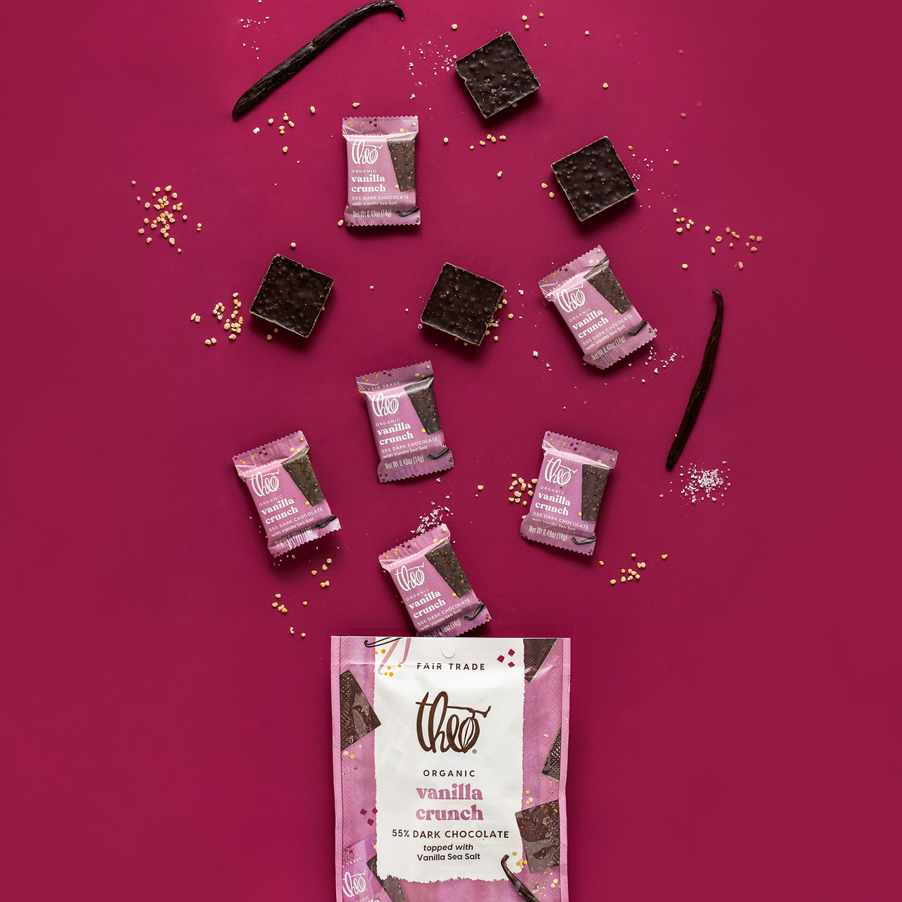 Theo Organic Vanilla Crunch dark chocolate bars with vanilla sea salt and packaging on a pink background