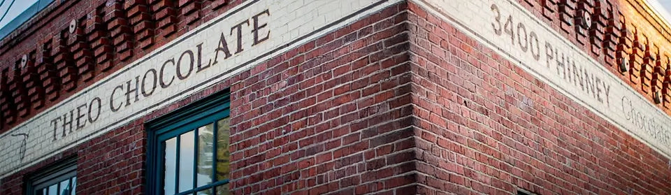 Brick building with 'THEO CHOCOLATE' and address '3400 PHINNEY' on the facade.