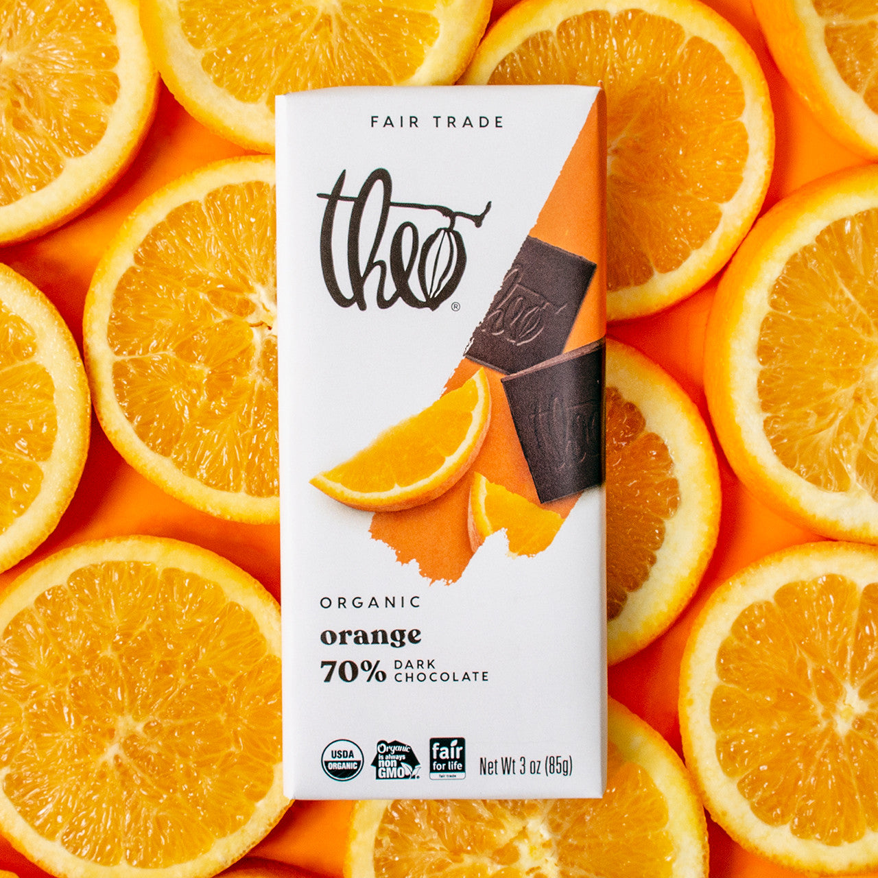 Theo Organic Orange Dark Chocolate bar surrounded by sliced oranges