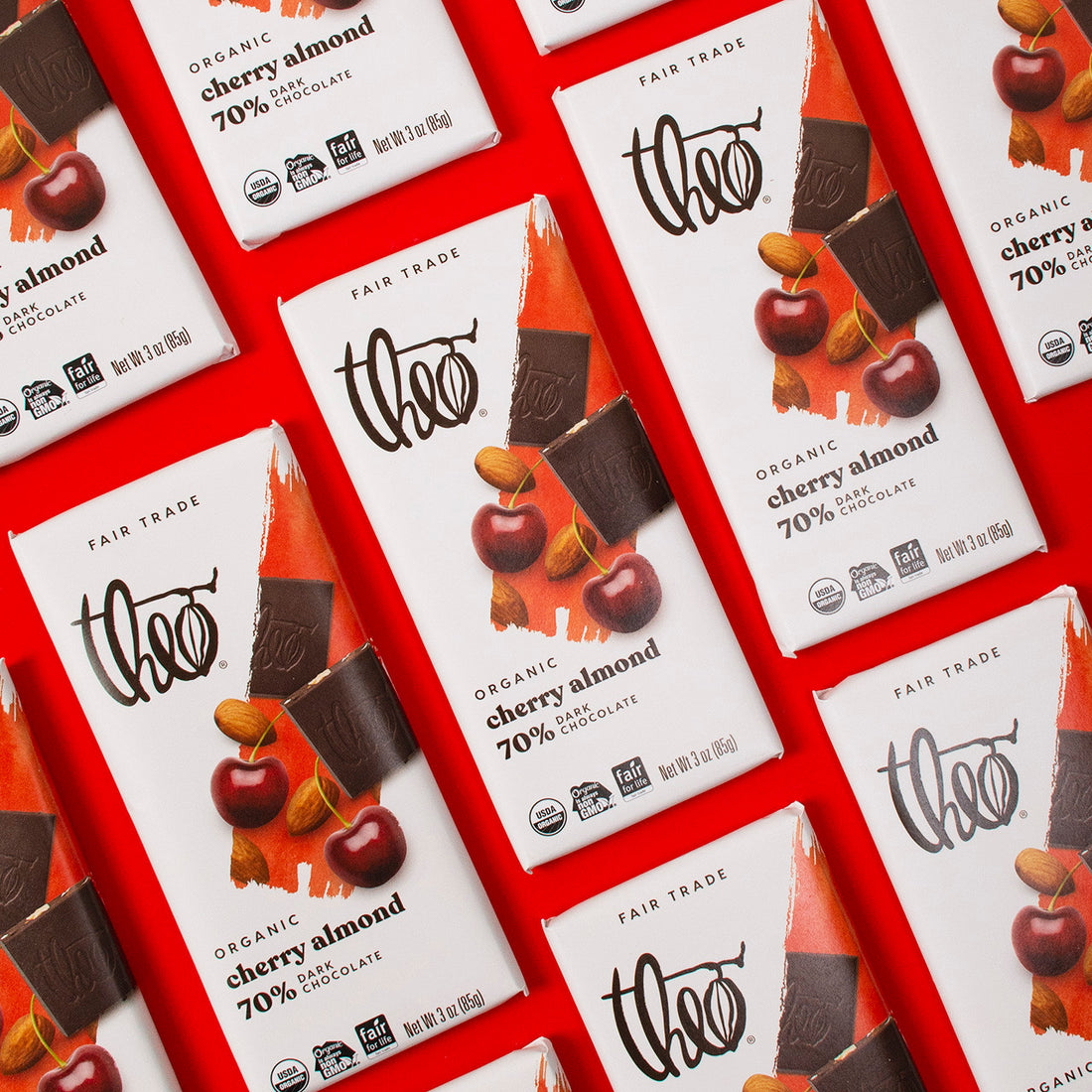 Multiple Theo Organic Cherry Almond 70% Dark Chocolate bars on a red background
