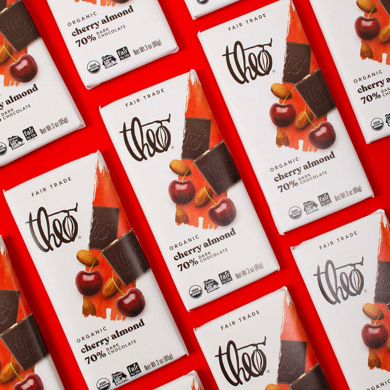 Multiple Theo Organic Cherry Almond 70% Dark Chocolate bars on a red background