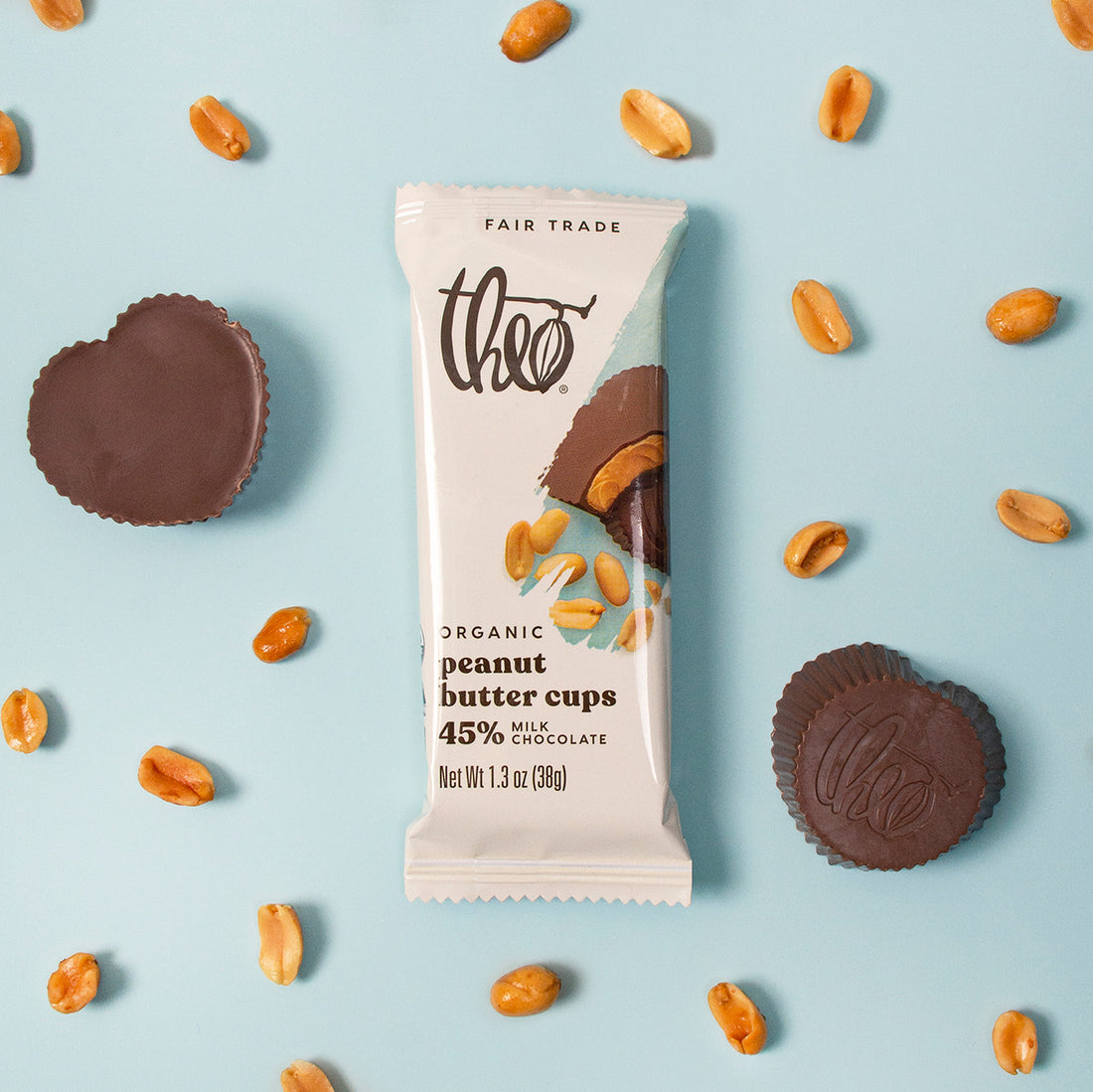 Theo organic peanut butter cups chocolate bar with peanut butter cups and peanuts on a light blue background