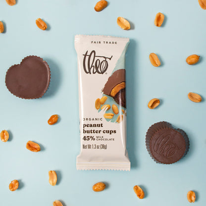 Theo organic peanut butter cups chocolate bar with peanut butter cups and peanuts on a light blue background