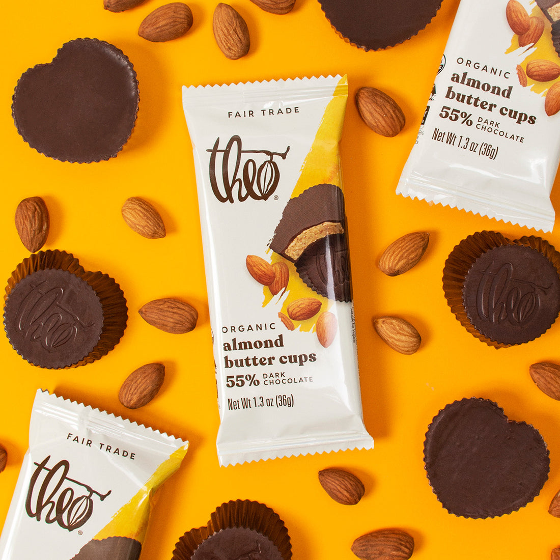 Heart shaped Theo Organic Almond Butter Cups with packaging on a yellow background