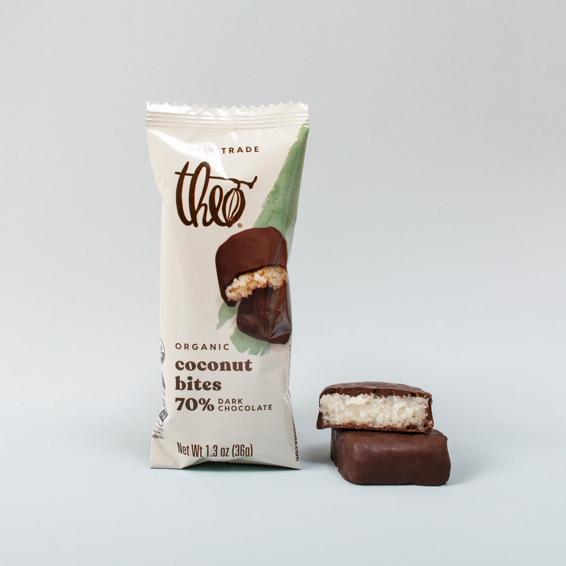 Packaged Theo Organic Coconut Bites with two chocolate covered coconut pieces and a gray background