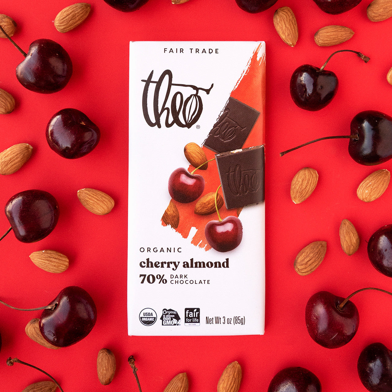 Theo Organic Cherry Almond 70% Dark Chocolate bar packaging on a red background with cherries and almonds.