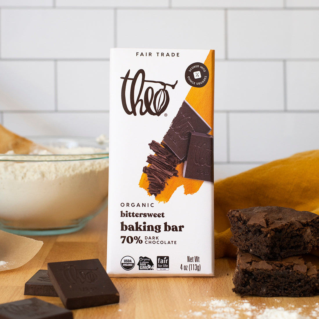 Theo Organic Bittersweet Baking Bar on a kitchen counter with brownies and flour.
