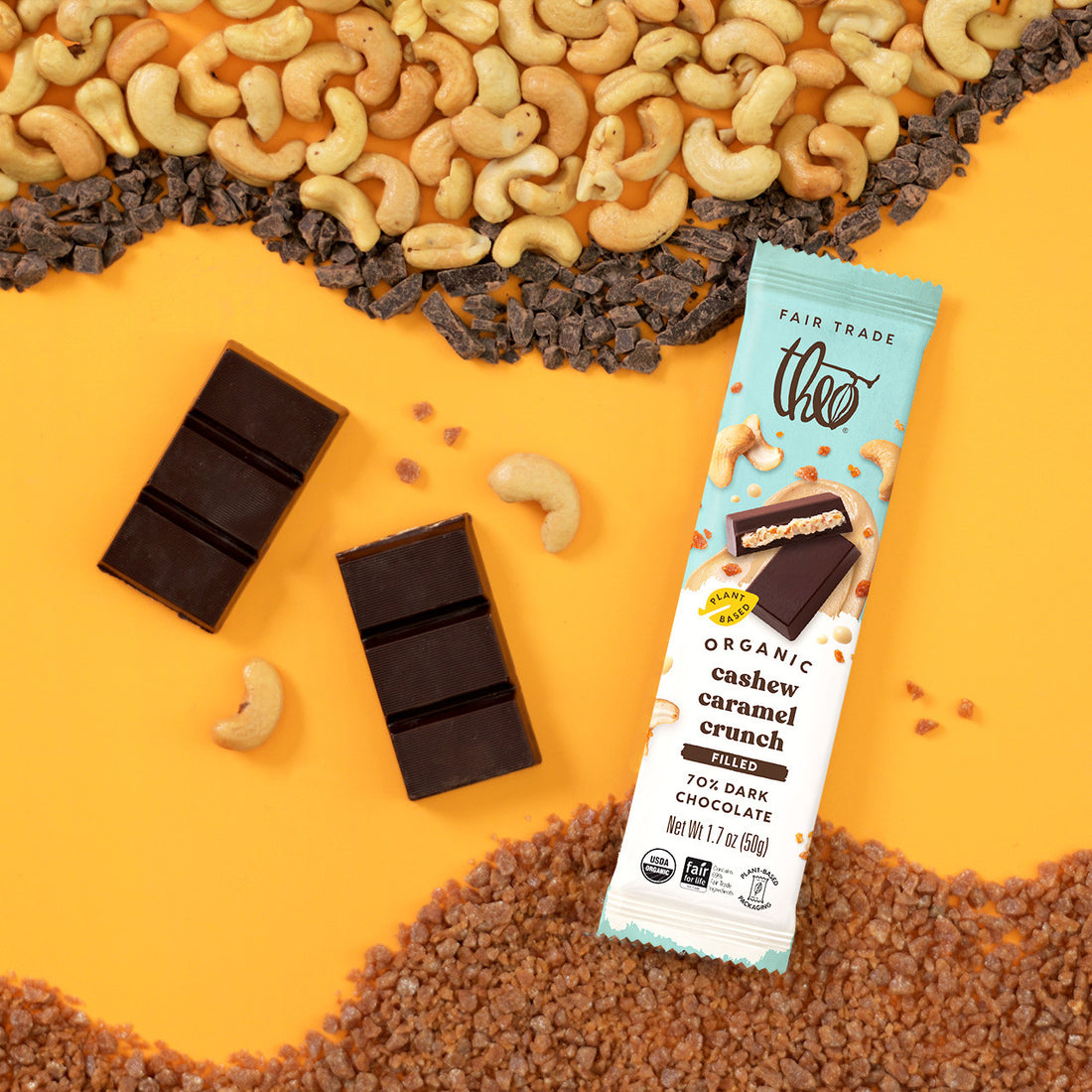 Theo Organic cashew caramel crunch dark chocolate bar with cashews, caramel, and dark chocolate on a yellow background