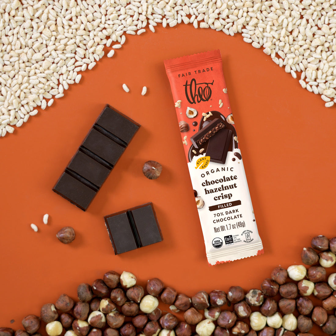 Filled chocolate bar with crispy pieces and hazelnuts on an orange background