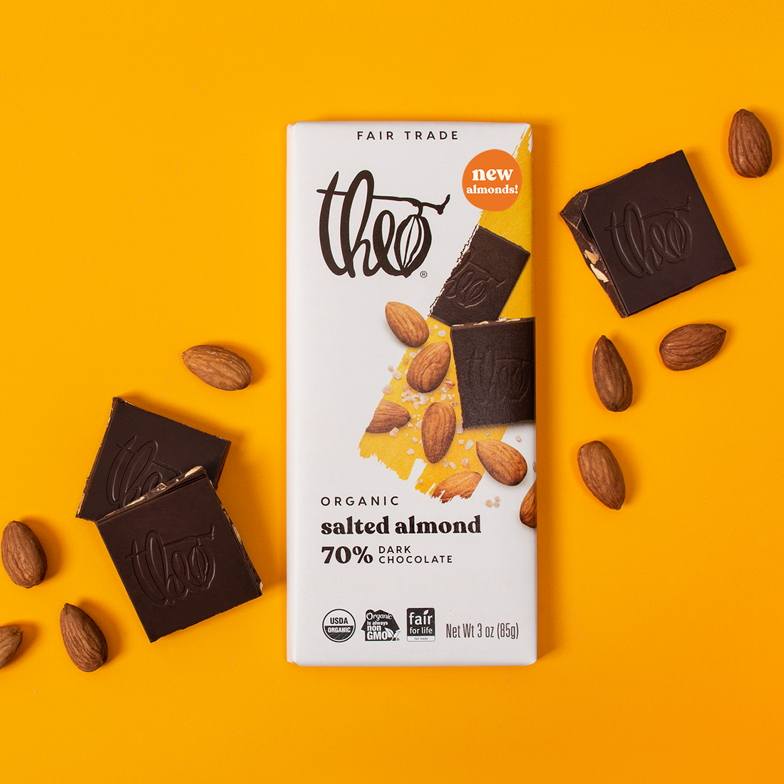 Theo Organic Salted Almond 70% Dark Chocolate bar on an orange background with chocolate pieces and almonds.
