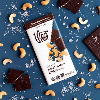 Theo Organic Salted Cashew 85% Dark Chocolate bar with cashews and sea salt on a blue background
