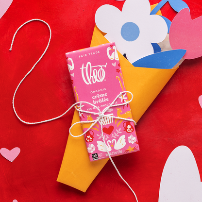 Theo organic crème brélèe chocolate bar on a red background with decorative elements.