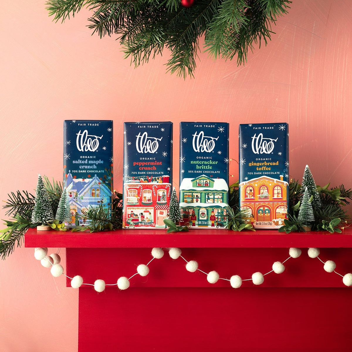 Four Theo holiday bars lined up on a festive red mantle
