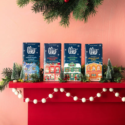 Theo holiday bars including Salted Maple Crunch lined up on a festive red mantle