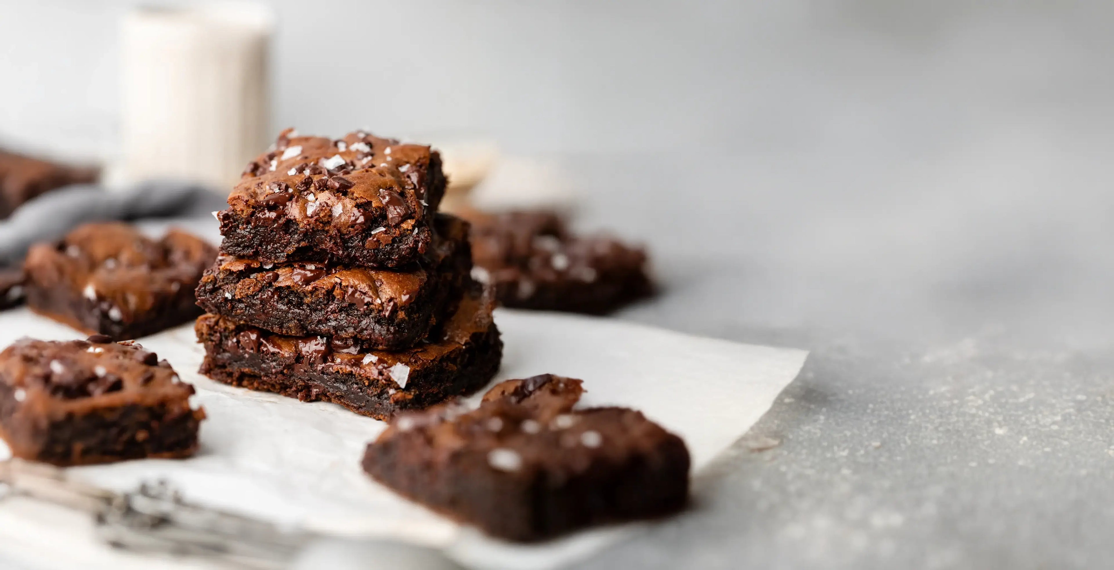 Stack of brownies on a piece of parchment paper with a blurred background